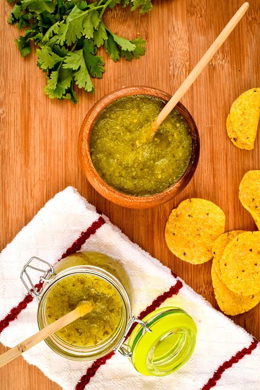 How to Make Tomatillo Salsa_16 A wooden bowl of tomatillo salsa, a jar of tomatillo salsa, cilantro and tortilla chips in the background.
