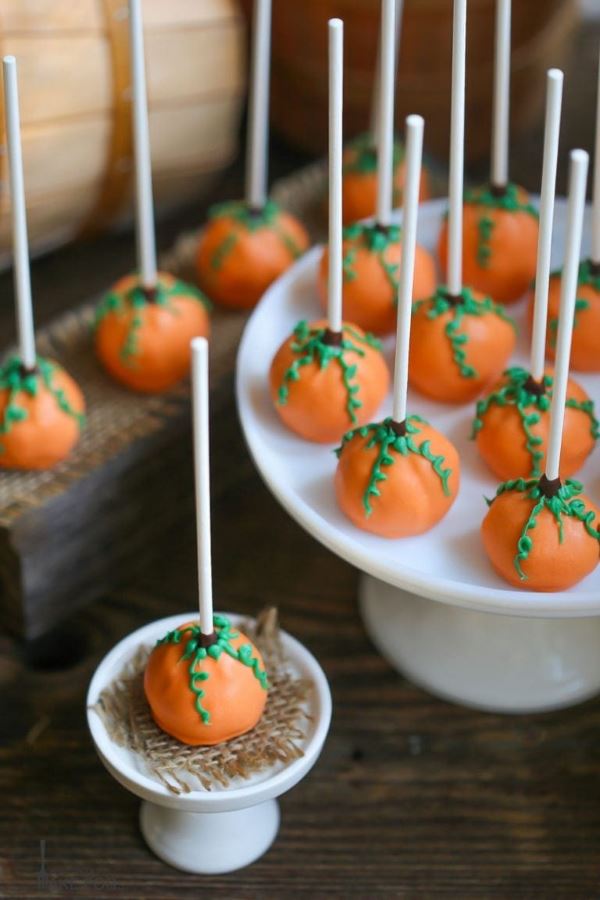Cake pops that look like pumpkins, upside down on a tray.