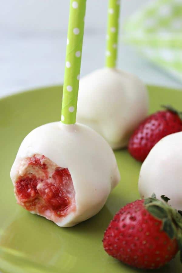 Strawberry shortcake cake pops, the inside showing, on a green plate.