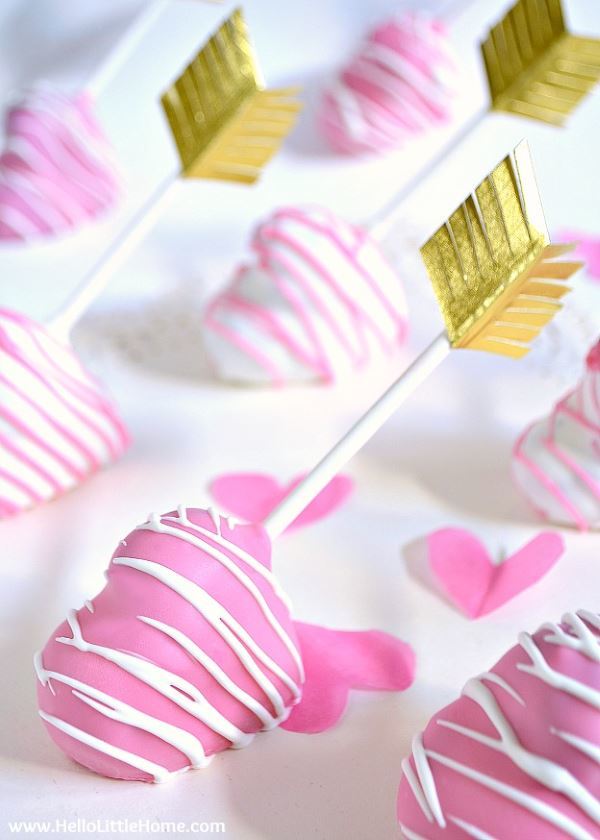 Pink heart shaped cake pops with golden arrows.