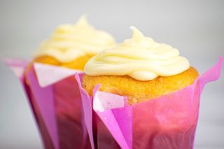 2 cupcakes with buttercream frosting in purple wrappers.