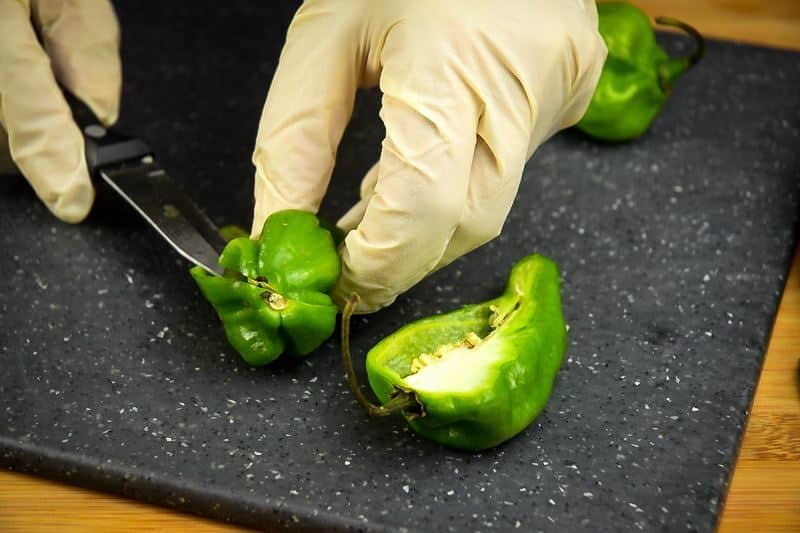 How to Grill Jalapeño Poppers_2 Slicing jalapeno peppers in half on a cutting board with rubber gloves.