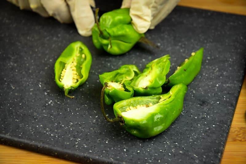 How to Grill Jalapeño Poppers_3 Slicing jalapeno peppers in half on a cutting board with rubber gloves.