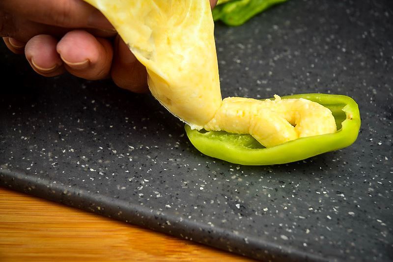 How to Grill Jalapeño Poppers_5 Adding cheese through a piping bag into a jalapeno pepper slice.
