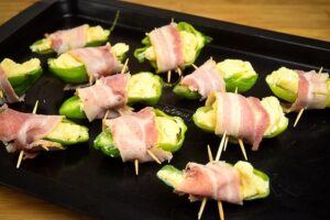 Raw jalapeno poppers on a baking sheet.