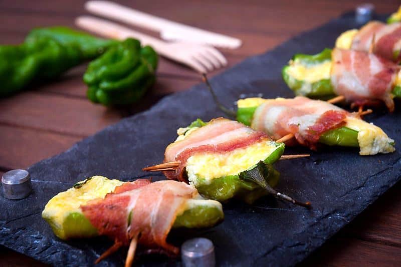 Grilled jalapeno poppers on a black rectangular serving tray.