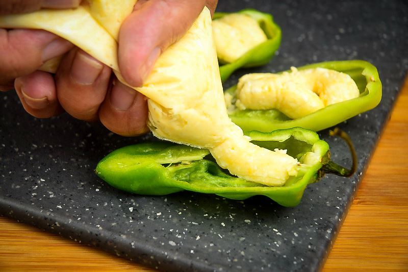 Adding cheese through a piping bag into a jalapeno pepper slice.