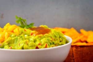 A bowl of guacamole with mango and passion fruit coulis.