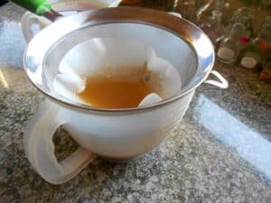 Maple syrup filtering into a measuring cup.