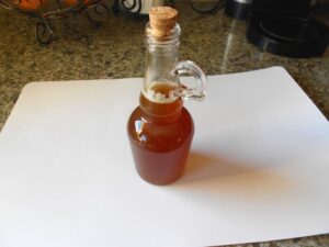 A bottle of maple syrup on a white cutting board.