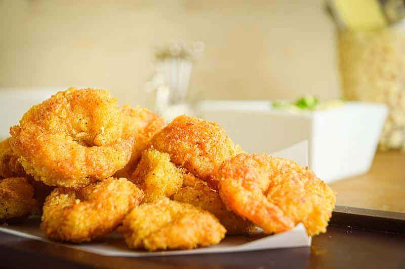 Electric Skillet Coconut Shrimp with Curry Mayo 2 Fried coconut shrimp on a black serving tray, curry dip on the side.