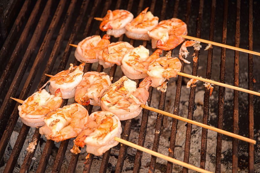 Cooked jumbo shrimp skewers on bbq.