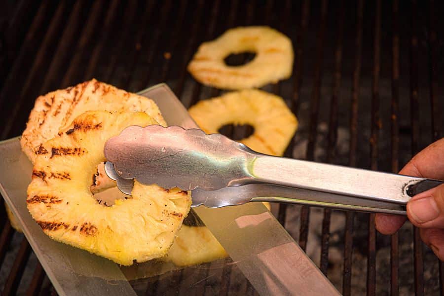How to Grill Pineapple Slices_11 Pineapple slices on the grill, being transferred to a glass plate.