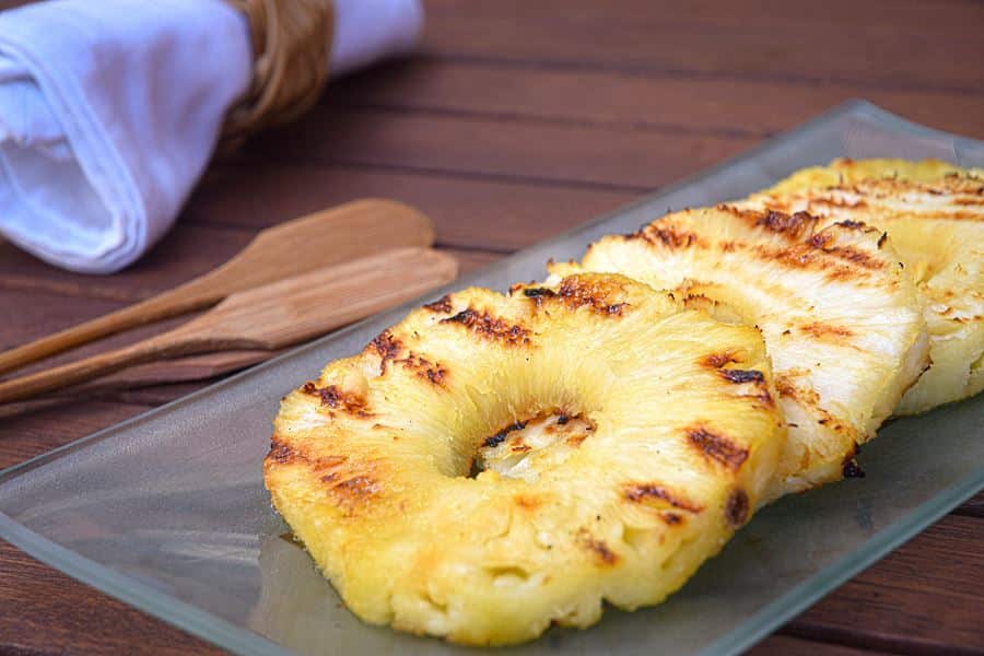 How to Grill Pineapple Slices_12 Grilled pineapple slices on a glass serving plate.