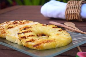 Grilled pineapple slices on a glass serving plate.