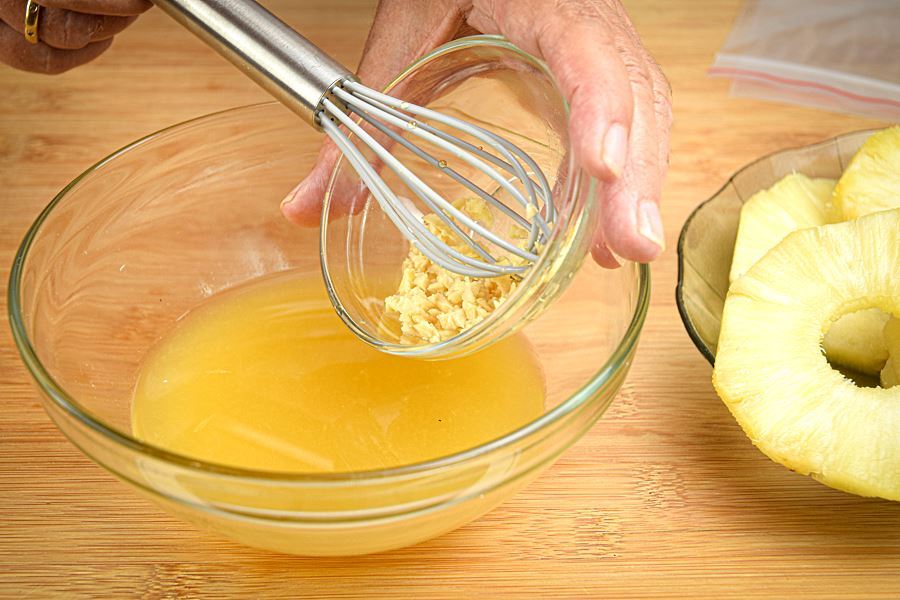 How to Grill Pineapple Slices_3 Ginger, chopped, being added to bowl of pineapple marinade.
