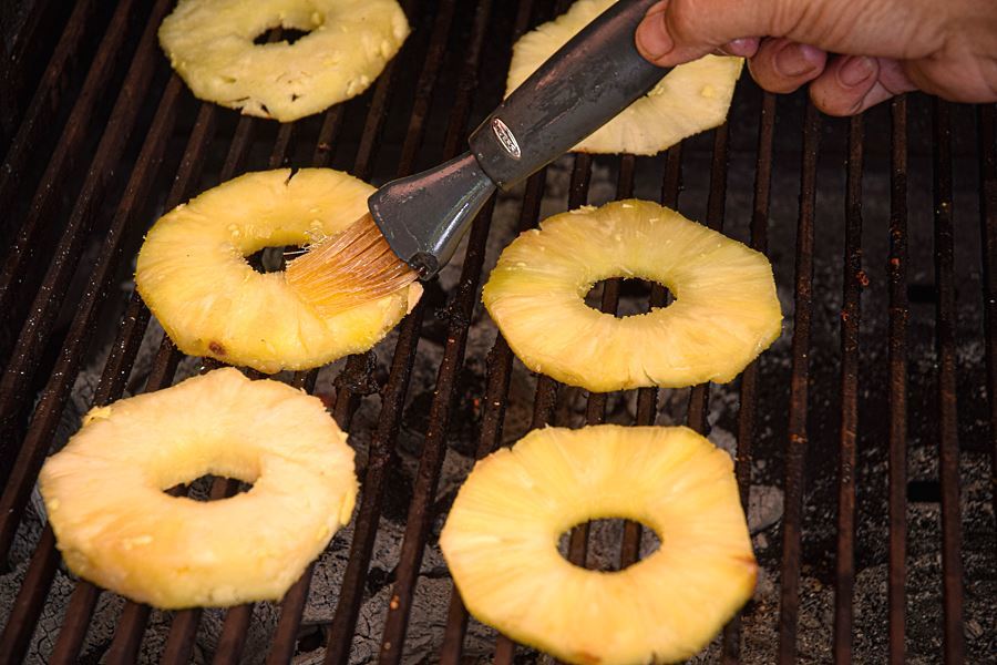 How to Grill Pineapple Slices_8 Pineapple slices on the grill, hand brushing them with pastry brush.