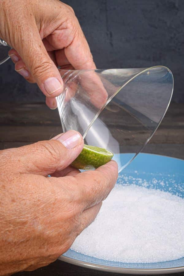 Martini glass getting rubbed with a lime wedge.