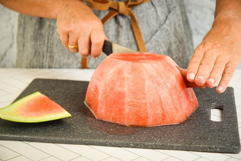 A woman slicing sticks out of a watermelon.