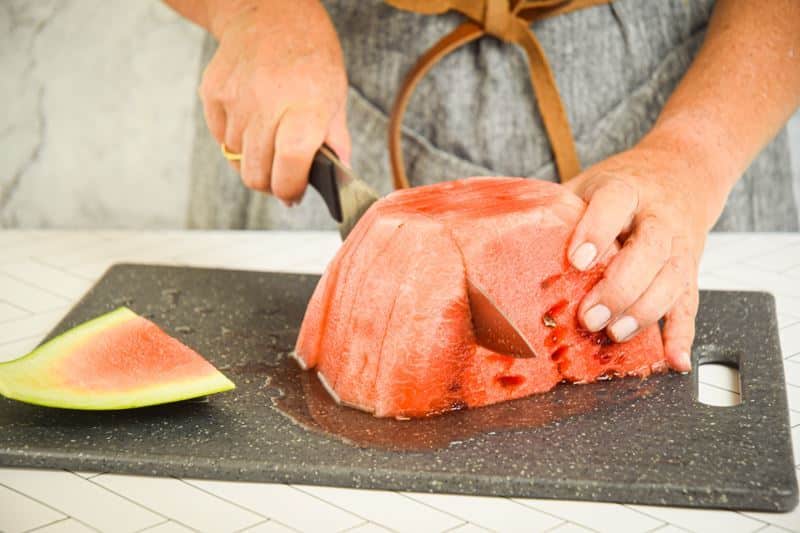 A woman slicing sticks out of a watermelon.