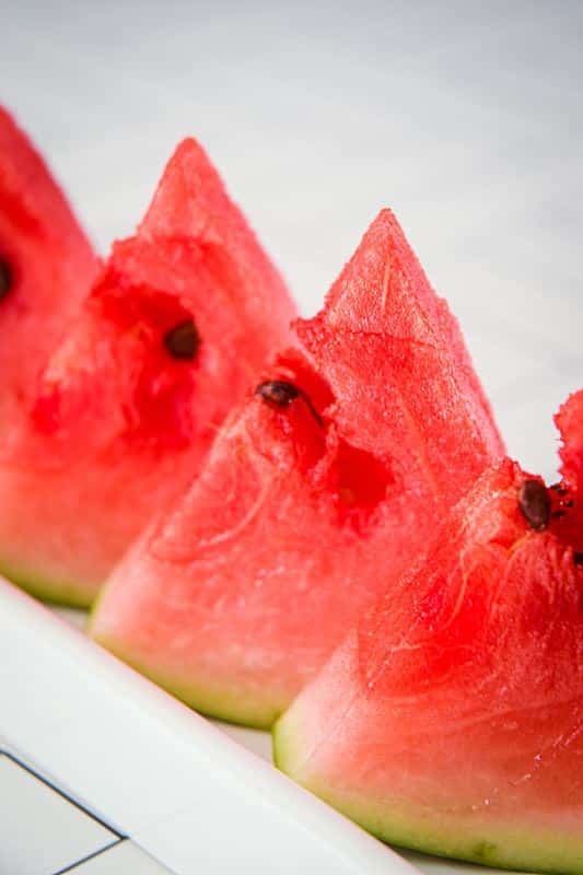 Triangle watermelon slices on a white serving dish.