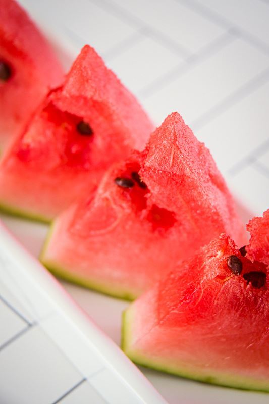 Triangle watermelon slices on a white serving dish.