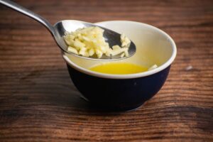 Chopped garlic in a spoon, melted butter in small bowl.
