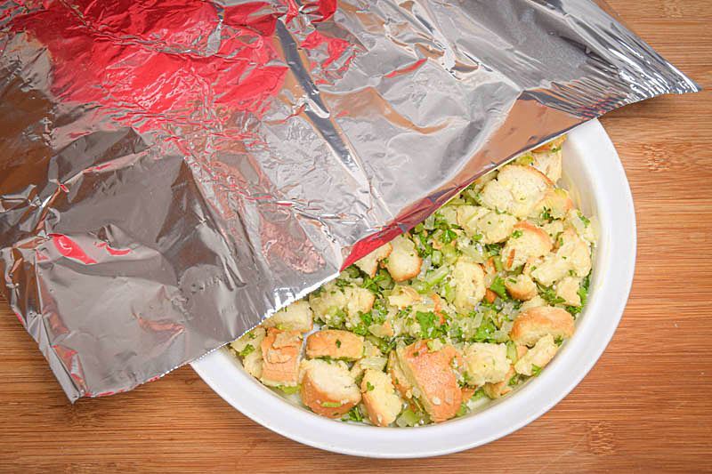 Stuffing in a bowl, foil over top, wooden background.