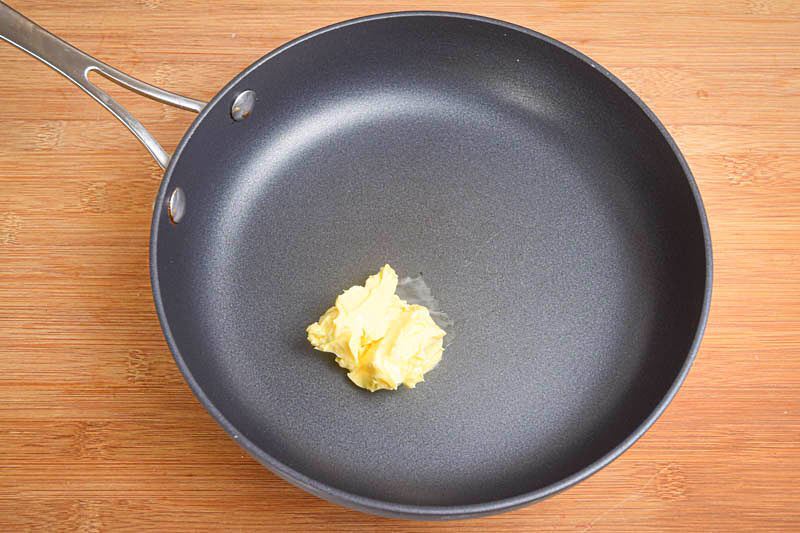 Butter in a frying pan, wooden background.