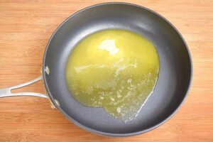 Butter in a pan, wooden background.