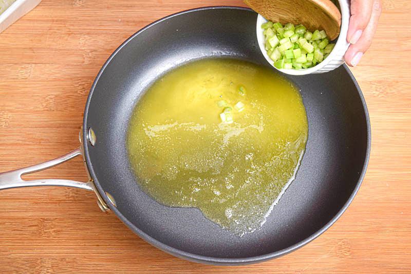 Butter and onions in a pan, wooden background.