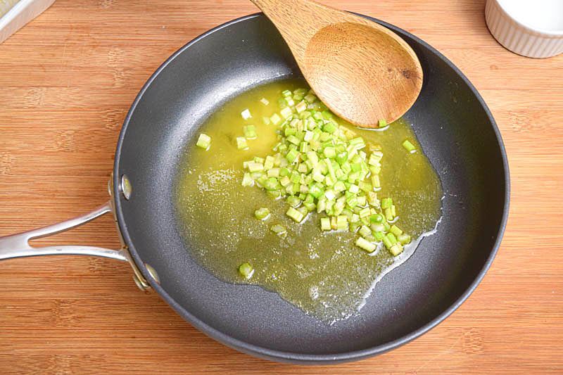 Onions and butter in a pan, wooden background.