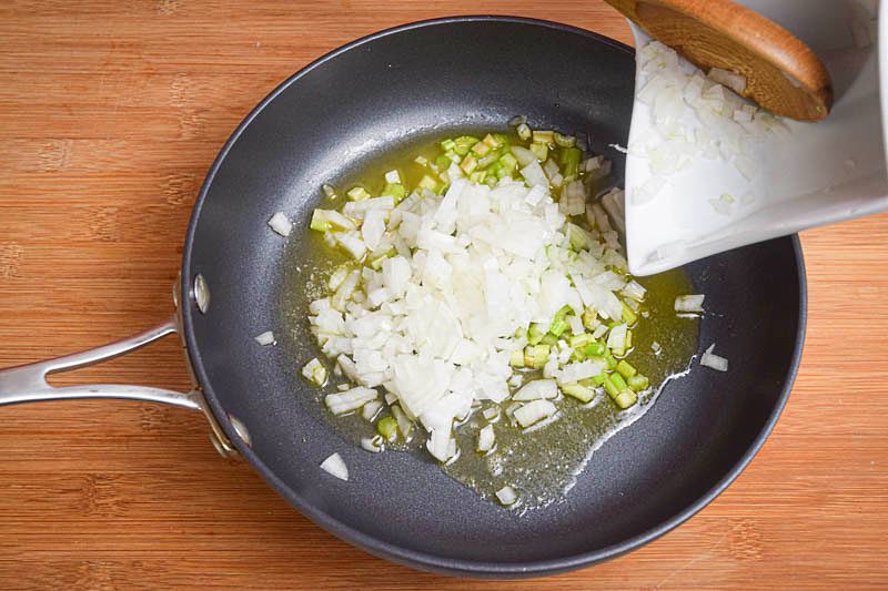 Onions and butter in a pan, wooden background.