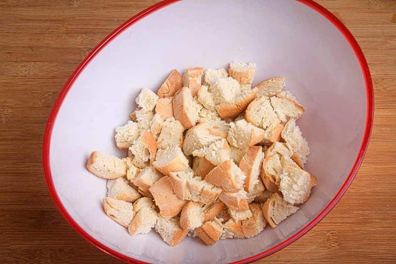 Cubed bread in a bowl, wooden background.