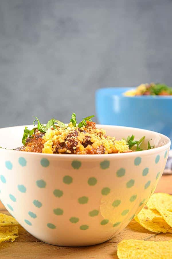 Electric Skillet Chili in a white bowl with blue polka dots, tortilla chips on the side.