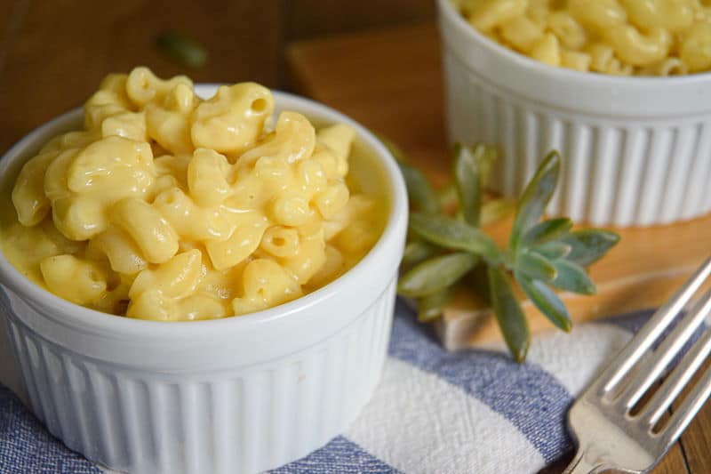 Electric Skillet Mac and Cheese in white bowls, a blue and white striped kitchen towel underneath and a succulent plant on the side.