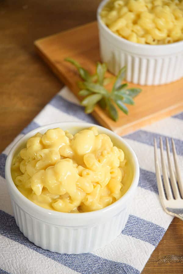 Electric Skillet Mac and Cheese in white bowls, a blue and white striped kitchen towel underneath and a succulent plant on the side.