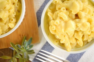 Electric Skillet Mac and Cheese in white bowls, a blue and white striped kitchen towel underneath and a succulent plant on the side.