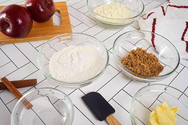 Apple crisp prepped ingredients in bowls on a white background.