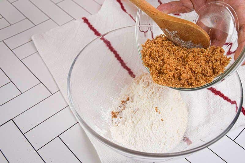 Sugar being added to a bowl of flour.