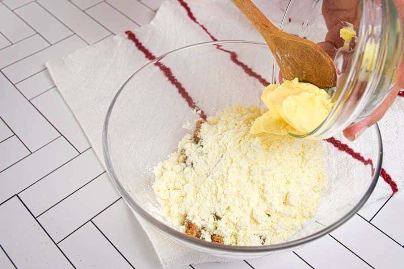 How to Make Apple Crisp_9 Butter being added to bowl of apple crisp ingredients.