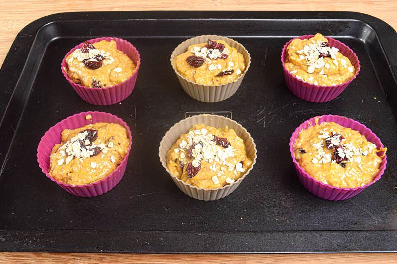 Pumpkin Muffins with cranberries in silicone muffin molds on a baking sheet.