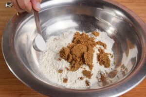 A metal bowl of pumpkin muffin batter being made.