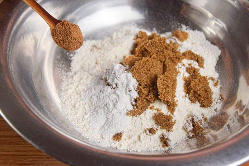 A metal bowl of pumpkin muffin batter being made.