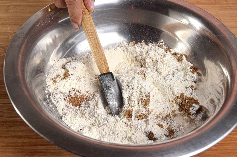 A metal bowl of pumpkin muffin batter being made.