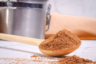 Pumpkin pie spice on a wooden spoon, metal canister in the background.