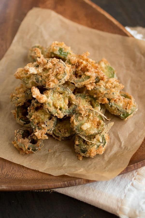 Deep fried candied jalapeno slices in a wooden dish.