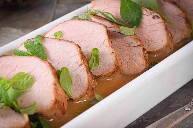 Sliced pork tenderloin in a white rectangular dish.