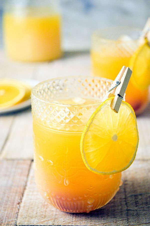 Fall Pumpkin Party Punch in a clear glass with a thin orange slice garnish clipped on with a clothespin.