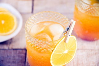 Fall Pumpkin Party Punch in a clear glass with a thin orange slice garnish clipped on with a clothespin.